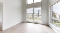 Located at 520 1st St E in North Vancouver, BC, this thoughtfully designed two-bedroom, two-bathroom residence offers a clean, modern aesthetic throughout. The open-concept layout connects the kitchen and living area seamlessly, with light wood-look flooring and crisp white walls creating a bright, airy atmosphere. The kitchen features white cabinetry, a subway tile backsplash, stainless steel appliances including a refrigerator, range, and built-in microwave, along with a central island with a sink. Large windows and a sliding glass door in the living area flood the space with natural light and provide direct access to a private balcony. Both bedrooms are well-proportioned with large windows; the primary bedroom includes a dedicated walk-in closet with built-in wire shelving. Additional closet storage is provided throughout the unit. The two bathrooms are finished in neutral tones, with one featuring a frameless glass sliding shower enclosure and stone-topped vanity. An in-unit laundry area houses a stacked washer and dryer. The hallway connects all rooms efficiently, contributing to a practical and well-organized floor plan suited for comfortable everyday living.