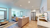 Located along the iconic Ocean Boulevard in Long Beach, this contemporary three-bedroom, two-bathroom residence offers a thoughtfully designed open-concept layout with modern finishes throughout. Light wood flooring flows through the main living areas, complementing the bright, airy ambiance created by recessed lighting and large windows.

The kitchen is a standout feature, equipped with stainless steel appliances, white upper cabinetry, light wood lower cabinets, and a center island with a clean white countertop — seamlessly connecting to the dining and living areas for effortless entertaining. The dining nook is framed by floor-to-ceiling windows that frame sweeping panoramic views of the Long Beach cityscape and beyond.

The living room features a distinctive curved architectural column and opens to additional views, giving the space a refined, modern character. Each bedroom benefits from expansive windows with breathtaking high-rise city views, plush carpeting, and clean white walls. The primary bedroom is generously proportioned with ample natural light.

Both bathrooms are finished with wood-look flooring, neutral tile surrounds, built-in shelving, and warm, functional fixtures. A hallway and dedicated closet complete the layout. The overall aesthetic is clean, contemporary, and elevated — ideal for those seeking modern urban living with spectacular views.