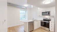 Located at 168 Wellington St in Kingston, Ontario, this efficiently designed one-bedroom, one-bathroom unit offers a thoughtfully arranged single-floor layout. Light hardwood flooring runs throughout, complementing the bright, neutral colour palette that gives the space an open and airy feel.

The kitchen is a standout feature, outfitted with crisp white shaker-style cabinetry, white quartz countertops, and a full suite of stainless steel appliances including a refrigerator, electric range, over-the-range microwave, and dishwasher. A double stainless steel sink is positioned beneath a window, allowing natural light into the cooking area. Exposed silver ductwork adds an industrial accent along the upper portion of the space.

The bedroom is a well-proportioned room with a window that brings in natural light, continuing the clean, minimal aesthetic found throughout the unit. White panelled doors with matte black hardware provide access to the bedroom, bathroom, and a closet, adding a refined contrast to the soft neutral walls.

The bathroom maintains the same clean, modern design with light flooring and white walls. The unit also includes an in-unit laundry area, adding everyday convenience. Overall, this space presents a functional, modern environment well-suited for comfortable urban living in downtown Kingston.