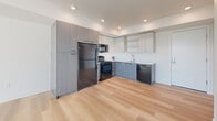 Located in Wilsonville, Oregon, this thoughtfully designed one-bedroom, one-bathroom residence offers a clean, contemporary aesthetic throughout. Light wood-toned flooring flows seamlessly across the entire unit, creating a warm and cohesive atmosphere.

The open-concept kitchen and living area serves as the heart of the home. The kitchen is well-appointed with dark wood grain cabinetry contrasted by crisp white upper cabinets, white quartz countertops, a stainless steel sink, and black appliances including a refrigerator, range, microwave, and dishwasher. Recessed lighting illuminates the space efficiently. The adjoining living area is bright and airy, benefiting from large windows that invite generous natural light and views of the surrounding greenery. A ceiling fan adds comfort and functionality.

The bedroom is a comfortable retreat, featuring its own ceiling fan, a wall-unit HVAC system, and a window that frames outdoor views. Two closets provide ample storage throughout the unit.

The bathroom is clean and functional, finished with light wood flooring, a white vanity with warm wood cabinetry, and a full tub/shower combination. The overall design of this residence emphasizes simplicity, modern finishes, and practical living in a compact yet efficient floor plan.