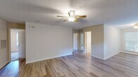 Located at 2813 Spring Garden St in Greensboro, NC, this single-floor residence offers three bedrooms and two bathrooms within a practical, well-organized layout. The living room features light-toned hardwood-style flooring, neutral walls, and a ceiling fan with a light fixture, creating a bright and comfortable gathering space. A small window near the front entry allows for additional natural light to filter in. The kitchen is outfitted with warm wood cabinetry extending to the ceiling, white appliances including a refrigerator, electric range, and built-in microwave, and light countertops that complement the overall neutral palette. The bedrooms are carpeted for comfort, each equipped with a ceiling fan and closet space — one featuring double doors that open to a built-in shelving system. The primary bedroom offers a window with blinds that invites natural light. Both bathrooms are finished with wood-toned vanity cabinetry, light stone-look countertops, and brushed nickel fixtures, maintaining a consistent and clean aesthetic throughout. Textured ceilings are present across the home, adding a classic residential character. The single-story floor plan connects seamlessly through a central hallway, making the space feel cohesive and easy to navigate.