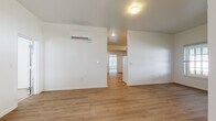 This two-story townhouse in Niantic, Connecticut offers a practical and well-appointed layout across two floors. The entry level introduces a covered entryway with a nautical-style wall sconce and lap-siding detail, lending a coastal character to the arrival experience. A dark-framed barn-style door leads into the main living area, where light wood-style flooring extends throughout, complementing the clean white walls and creating a bright, open atmosphere.

The kitchen is equipped with gray cabinetry, ample counter space, a full suite of white appliances including an electric range with overhead microwave, dishwasher, and sink. The adjacent living area is generously proportioned with recessed lighting and a wall-mounted mini-split system for climate control. A half bath is conveniently located on this level.

The upper floor houses three bedrooms, each featuring wood-style flooring and windows that allow natural light and views of the surrounding greenery. The primary bathroom includes a double-sink vanity with a white countertop and a walk-in shower, while the second full bathroom offers a single vanity and a shower-tub combination. An attached one-car garage with automatic opener and a paved driveway rounds out this townhouse's functional amenities.