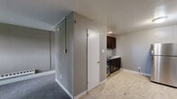 This single-floor unit at 6613-6635 Charles St in Philadelphia, PA offers a practical and efficiently arranged layout. The living room is carpeted in grey and provides a comfortable, open feel, with a window that allows natural light to filter in and a baseboard heating unit running along one wall. Neutral grey walls throughout the unit create a consistent, understated aesthetic.

The kitchen is situated adjacent to the living area and features dark espresso-toned cabinetry, a gas range, a sink, and light tile flooring, offering functional workspace for everyday cooking. A tiled backsplash adds a clean finishing detail to the kitchen area.

The bathroom includes classic white subway tile wainscoting along the lower walls, a vanity with under-sink storage, a medicine cabinet with mirror, and a toilet, presenting a straightforward and clean design.

Two closets provide additional storage options within the unit. The overall layout is compact yet well-organized, making efficient use of the available space. The combination of carpet in the living area and tile flooring in the kitchen and bathroom adds practical variety underfoot throughout the unit.
