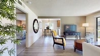 Located at 1300 Adams Ave in Costa Mesa, California, this single-story home offers three bedrooms and two bathrooms with a well-designed, functional layout. The living room features wood-style flooring, a textured ceiling, and a sliding glass door that fills the space with natural light and opens to an outdoor patio with greenery views, creating a seamless indoor-outdoor feel. The adjoining dining area connects naturally to the galley-style kitchen, which is outfitted with warm wood cabinetry, granite-style countertops, and white appliances, all illuminated by a window overlooking the exterior.

The bedrooms are carpeted and comfortably sized, each offering a calm, neutral palette with natural light from exterior windows. The primary bedroom is notably spacious and is accompanied by a dedicated en-suite bathroom featuring a wide dual-sink vanity with wood cabinetry and large mirrors, as well as direct access to a generous walk-in closet with built-in shelving and hanging rods. The second bathroom includes a combined tub and shower with a sliding glass enclosure. Throughout the home, the design balances practicality and comfort, making it a well-appointed residence in the heart of Costa Mesa.