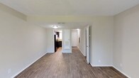 This 2-bedroom, 1-bathroom residence is spread across two floors, offering a practical and comfortable layout suited for a variety of lifestyles. Throughout the living areas, durable wood-style flooring adds warmth and visual continuity, complemented by neutral-toned walls and textured ceilings that create a clean, move-in-ready aesthetic.

The living area is open and well-proportioned, with a sliding glass door fitted with vertical blinds that invites natural light and provides direct views of the surrounding greenery outdoors. The layout connects seamlessly to the kitchen, which is a standout feature of the home. It is equipped with dark espresso cabinetry, granite-style countertops, black appliances including a gas range, and a stainless steel sink positioned beneath a window — offering both style and functionality.

Both bedrooms are generously sized and filled with natural light courtesy of well-placed windows with blinds. The wood-style flooring continues throughout, and each room offers ample wall space for flexible furniture arrangements.

The full bathroom is neatly finished with a tub-shower combination, a dark-cabinetry vanity with a white countertop, and a wall-mounted mirror with overhead lighting. Clean white fixtures complete the space with a crisp, timeless look. Overall, this residence presents a cohesive and functional living environment across its two floors.