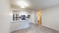 Located at 4000 N First Ave in Tucson, AZ, this two-bedroom, one-bathroom residence offers a thoughtfully arranged single-floor layout with a clean, updated aesthetic throughout. Light-toned wood-look flooring flows consistently across all rooms, complemented by neutral walls and textured ceilings that lend a cohesive, modern feel.

The open living area greets you at the entry, featuring a window with blinds that brings in natural light and a wall-mounted HVAC unit for individual climate control. A flush-mount ceiling fixture provides warm overhead lighting.

The kitchen is efficiently designed with white cabinetry, white quartz-style countertops, and a gray subway tile backsplash. Stainless steel appliances include a refrigerator and an electric range with a hood vent. A peninsula counter extends into the living space, creating a natural divider and additional workspace.

Both bedrooms are light and calm, each featuring windows with blinds, wall-mounted HVAC units, and ample wall space. The primary bedroom offers a comfortable footprint well-suited for standard furnishings.

The full bathroom includes a single-sink vanity with storage, a toilet, and a tub-shower combination with a curtain rod, all finished with the same wood-look flooring and neutral tones found throughout the home.