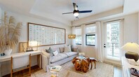 Located at 2480 First St in Fort Myers, FL, this thoughtfully designed one-bedroom, one-bathroom residence offers a bright and cohesive coastal aesthetic across a single floor. The open-concept living, dining, and kitchen area serves as the heart of the home, anchored by warm hardwood-style flooring, recessed lighting, and a tray ceiling detail. The kitchen is outfitted with two-tone cabinetry in white and light wood, stainless steel appliances, a white quartz countertop island with bar seating, a tile backsplash, and under-cabinet lighting. The living area features a ceiling fan with light fixture, large windows with sheer drapes, and direct access to a private patio, allowing abundant natural light and outdoor views. The bedroom is a serene retreat with a ceiling fan, a wide picture window overlooking lush surroundings, and wood-look flooring. The bathroom includes a combination tub and shower, light wood vanity with a white countertop, and matte black hardware accents. Additional features include two closets and an in-unit laundry area, rounding out a functional and stylish floor plan well-suited to the Florida lifestyle.
