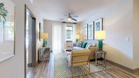 This single-floor residence offers a thoughtfully designed layout that balances comfort and modern style throughout every room. The living area serves as the heart of the home, featuring wood-style plank flooring, a ceiling fan with light fixture, and a large window with sliding door access that fills the space with natural light. Neutral walls are complemented by tasteful décor, creating a warm and inviting atmosphere.

The kitchen is a standout feature, showcasing rich dark cabinetry, stainless steel appliances including a range, microwave, and French door refrigerator, and a mosaic tile backsplash. Light stone countertops extend to a breakfast bar with seating, offering both functionality and a casual dining option. Pendant lighting adds a refined finishing touch.

Two bedrooms provide comfortable retreats, each with plush carpeting, large windows dressed with sheer curtains, and ample closet space — one featuring a walk-in closet with built-in shelving. Both bedrooms carry a calm, neutral palette suited for rest and relaxation.

The two bathrooms are finished with large-format tile flooring and contemporary dark cabinetry. One bathroom includes a soaking tub with tiled surround, while the other features a walk-in glass shower and an adjacent linen storage area, offering practical elegance throughout.