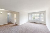 Located at 639 Sligo Ave in Silver Spring, MD, this 2-bedroom, 1-bathroom residence offers a well-organized single-floor layout designed for comfortable everyday living. The combined living and dining area serves as the heart of the home, featuring neutral carpet flooring, crisp white walls, and a large picture window that frames outdoor greenery and fills the space with natural light. A baseboard heating unit runs beneath the window, keeping the area functional year-round. The galley-style kitchen is efficiently designed with white cabinetry, granite-look countertops, hardwood-style flooring, a gas range, full-size refrigerator, and in-unit washer. A window above the sink brings in additional natural light. Both bedrooms are carpeted and bright, each featuring a dedicated closet — one with bifold doors and another with a walk-in style layout with shelving. The bedrooms offer quiet, comfortable retreats with natural light from individual windows. The full bathroom includes a soaking tub with shower, a white vanity with under-sink storage, and a window for ventilation. A hallway connects the rooms, and the unit offers a total of four closets for generous storage throughout. The entry area transitions from carpet to hard flooring, providing a practical foyer space.