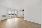 Located at 900 Phillips St in Vista, CA, this well-appointed one-bedroom, one-bathroom unit offers a clean, modern aesthetic throughout its efficiently designed single-floor layout. Light wood-look flooring flows seamlessly across all rooms, complementing the crisp white walls and creating a bright, cohesive atmosphere.

The living room is the heart of the unit, featuring a ceiling fan, recessed lighting, and a sliding glass door that opens onto a private balcony with outdoor views — filling the space with generous natural light. A wall-mounted HVAC unit provides climate control.

The galley-style kitchen is thoughtfully updated with white shaker cabinetry, matte black hardware, stone-look countertops, an undermount sink with a matte black faucet, and a full suite of stainless steel appliances including a range, microwave, and refrigerator.

The bedroom offers a comfortable footprint with a window fitted with blinds for natural light and privacy, along with a mirrored sliding-door closet that adds depth and storage.

The bathroom is finished in a modern monochrome palette, featuring a white vanity with stone countertop, a tub/shower combo, and matte black fixtures and accessories throughout.

A connecting hallway with recessed lighting ties the layout together, with a bold black paneled entry door serving as a striking design detail.