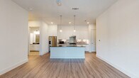 Located at 10400 Research Blvd in Austin, TX, this thoughtfully designed one-bedroom residence offers a well-appointed, single-level layout with a clean, modern aesthetic throughout. The open-concept kitchen and living area serves as the heart of the home, featuring crisp white shaker cabinetry extending to the ceiling, dark quartz countertops, a stylish penny-tile backsplash, stainless steel appliances including a French door refrigerator and electric range, and a central island — all set atop warm wood-look vinyl flooring. Large floor-to-ceiling windows and a glass door in the living area flood the space with natural light and offer views of the surrounding greenery. The dining area flows naturally from the kitchen, creating a cohesive, versatile entertaining space. The generously sized primary bedroom is finished with plush carpet, a ceiling fan, and a large window that brings in ample daylight. It connects directly to a spacious walk-in closet equipped with dual hanging rods and built-in shelving. A dedicated laundry room with in-unit washer and tile flooring adds everyday convenience. Neutral wall tones and clean lines throughout give the space a bright, contemporary feel.