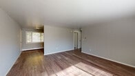 Located at 83 Main St in Newington, Connecticut, this single-floor unit offers a clean, updated interior with a cohesive design throughout. The open living area is finished with warm hardwood-style flooring and neutral gray walls, creating a bright and versatile space. Large windows fitted with horizontal blinds allow natural light to filter in while offering views of the surrounding greenery. Baseboard heating runs along the perimeter of multiple rooms, ensuring efficient climate control, and a wall-mounted air conditioning unit provides additional comfort.

The kitchen is well-appointed with crisp white shaker cabinetry, granite-style countertops, a stainless steel range with an overhead vent hood, and a stainless steel sink — providing a functional and attractive cooking space.

The bathroom stands out with its striking design, featuring dark slate-style tile on the walls surrounding the soaking tub, contrasted by white cabinetry, large-format gray floor tiles, and a bright window that brings in natural light and outdoor views.

The bedrooms continue the consistent flooring and neutral palette found throughout, each offering generous wall space and natural light. The overall layout is efficient and thoughtfully designed, making this a well-maintained and move-in ready space.