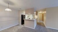 Located at 2122 E Bristol St in Elkhart, Indiana, this single-floor residence offers a practical and well-organized layout across two bedrooms and one bathroom. The open-concept living and kitchen area forms the heart of the home, where a peninsula-style kitchen with light wood cabinetry, white countertops, a gas range, dishwasher, and black refrigerator provides ample storage and workspace. Wood-look flooring runs throughout the kitchen, while plush carpeting extends into the living room and bedrooms, adding warmth and comfort. The living room is generously sized and filled with natural light from a large sliding glass door that opens to an outdoor patio area, creating a bright and airy atmosphere. The primary bedroom is spacious and includes a walk-in closet equipped with wire shelving for organized storage. The second bedroom offers comfortable proportions with carpeted flooring and easy access to the hallway. The full bathroom features a wide vanity with light wood cabinetry, a large mirror with Hollywood-style lighting, and wood-look flooring. A dedicated pantry closet with built-in shelving provides additional storage within the kitchen area. Throughout the residence, warm neutral tones, clean white trim, and wood-accented doors create a cohesive and inviting aesthetic.