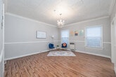 Located at 1733 N Cherokee Ave in the heart of Hollywood, Los Angeles, this single-floor unit offers a thoughtfully arranged layout comprising a living room, kitchen, two bathrooms, a closet, and an entrance. The living room serves as the centerpiece of the space, showcasing rich hardwood floors, elegant crown molding, and a striking ornate embossed tin ceiling with a crystal chandelier as its focal point. Multiple windows dressed with white blinds allow natural light to fill the room, while a built-in shelving unit adds functional character to the walls. The kitchen features classic white cabinetry with tile countertops, subway tile backsplash, and a gas range and refrigerator. A vintage-style black-and-white octagon tile floor lends timeless charm and is echoed in the bathrooms, where a pedestal sink, shower-tub combination, and clean white fixtures complete the classic aesthetic. A dedicated closet with a full-length hanging rod and shelf provides practical storage. The hallway connecting the rooms continues the warm hardwood flooring and features built-in drawers for additional storage. The overall ambiance blends vintage architectural character with a clean, neutral palette, creating a welcoming and functional space in a prime Los Angeles location.