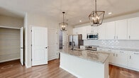 Located at 5060 Warner Rd in Westerville, Ohio, this well-appointed single-floor home showcases a thoughtfully designed interior with modern finishes throughout. The kitchen serves as the centerpiece of the home, featuring a large granite-topped island with an undermount sink and matte black faucet, crisp white shaker cabinetry, a decorative tile backsplash, and a full suite of stainless steel appliances including a refrigerator, range, microwave, and dishwasher. A pair of geometric bronze pendant lights add a contemporary touch overhead. The living and dining areas are bright and open, with light hardwood-style flooring and generous windows that bring in abundant natural light. Bedrooms offer plush carpeted flooring and neutral walls, creating a calm and versatile space. The primary suite connects directly to a private bathroom featuring a double-sink granite vanity with white cabinetry, a glass-enclosed subway tile shower, and warm wood-tone flooring, with access to a walk-in closet beyond. A conveniently located half bath off the main hallway mirrors the same refined finishes, including a granite vanity and white cabinetry. Throughout the home, clean lines, neutral tones, and quality materials combine to deliver a polished and move-in-ready living environment.