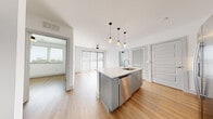 Located at 1003 16th Ave S in Nashville, TN, this contemporary 2-bedroom, 2-bathroom residence offers a well-designed, single-level layout with a clean, modern aesthetic throughout. Light hardwood flooring runs continuously across the entire space, creating a cohesive and bright atmosphere.

The open-concept kitchen and living area serves as the heart of the residence. The kitchen features a large central island with a quartz countertop and undermount sink, stainless steel appliances including a French door refrigerator, electric range, built-in microwave, and dishwasher, complemented by two-tone cabinetry and a herringbone tile backsplash. Stylish pendant lighting hangs above the island, adding a contemporary touch. The living area extends naturally from the kitchen and opens to an outdoor balcony through sliding glass doors, inviting natural light and city views.

The primary bedroom is a comfortable retreat with a ceiling fan, natural light, and direct balcony access. It is served by a private en-suite bathroom featuring a walk-in marble-tiled shower, a grey vanity with quartz countertop, and a large mirror. The second bedroom is bright and airy with a ceiling fan and window overlooking greenery. The second bathroom includes a soaking tub with marble tile surround, a grey vanity, and wood-look flooring. Both bedrooms include dedicated closets.
