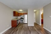 This 1-bedroom, 1-bathroom unit in Englewood, Colorado offers a functional and comfortable layout across a single floor. The open combined living and dining area is finished with durable wood-style plank flooring, neutral warm-toned walls, and a textured ceiling. Natural light enters through a large window fitted with vertical blinds, while a wall-mounted A/C unit and baseboard heating provide year-round climate control. The kitchen is equipped with rich wood cabinetry, granite-look countertops, a stainless steel refrigerator, gas range, and dishwasher, all complemented by the same wood-style flooring that flows throughout the main living areas. A hallway connects the living space to the bedroom and bathroom, offering convenient access to multiple closets for ample storage. The bedroom features plush carpeting, a ceiling fan with light, a window with vertical blinds, baseboard heating, and a closet. The full bathroom is tastefully finished with a wood-vanity, white countertop, a tub/shower combination clad in large-format tile with a decorative mosaic accent border, and a framed mirror. This well-designed unit provides a practical and inviting living environment in a convenient Englewood location.