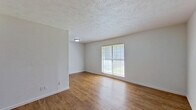 This efficient 2-bedroom, 2-bathroom single-floor unit offers a well-organized layout that maximizes every square foot of available space. The living area features warm wood-look flooring that flows consistently throughout the unit, complemented by crisp white walls and a textured ceiling that adds subtle visual interest. Natural light filters in through grid-pane windows with blinds, brightening the open living space.

The galley-style kitchen is lined with rich, dark wood cabinetry on both sides, providing ample storage and counter space with granite-style countertops. It is equipped with a white electric range, refrigerator, and dishwasher, making it a fully functional cooking space.

Both bedrooms are well-proportioned, each featuring wood-look flooring, white walls, and windows that allow natural light to enter. The primary bedroom offers a comfortable footprint, while each bedroom benefits from its own dedicated closet for convenient storage.

The bathrooms feature textured walls, vanities with light-toned countertops, large mirrors, and built-in cabinetry. One bathroom includes a notable extended vanity countertop area, adding functional surface space. The unit also features ceiling-mounted HVAC vents and a thermostat for climate control, ensuring year-round comfort throughout the home.