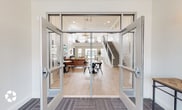 Located at 880 Arcadian Dr in Grand Ledge, Michigan, this two-story amenity center is designed with a clean, modern aesthetic that balances sophistication and functionality throughout. Entry is made through dramatic floor-to-ceiling glass double doors that immediately reveal the soaring two-story lobby, where light wood flooring, a grand staircase with sleek metal railings, and an elegant antler chandelier set a welcoming tone. The main lounge area anchors the ground floor with a striking white-painted stone fireplace wall, a large flat-screen display, and curated seating that invites relaxation. The expansive fitness center is a standout feature, offering soaring ceilings, abundant natural light from large windows, full-length mirrors, and a comprehensive range of equipment including treadmills, cycling bikes, rowing machines, power racks, and free weights. A dedicated cardio zone and a separate strength training area ensure a well-rounded workout experience. The billiards room provides a distinct atmosphere with deep navy paneled walls, herringbone hardwood flooring, industrial-style pendant lighting, and a full-size pool table. A business center offers a quiet, carpeted workspace with natural views of the surrounding community. Together, these spaces create a refined and fully appointed community hub.