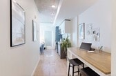 Located at 12322 102 Ave NW, this thoughtfully designed one-bedroom, one-bathroom unit offers a modern aesthetic with clean lines and light-toned finishes throughout. Light hardwood flooring runs continuously from the entry hallway through the main living areas, creating a cohesive and airy feel.

The entry hallway is sleek and functional, featuring recessed lighting, a full-length mirror, and a built-in closet with open shelving — a smart use of transitional space that sets the tone for the rest of the unit.

The living room is bright and inviting, benefiting from abundant natural light through a large sliding glass door that opens to a balcony with open city views. The exposed concrete ceiling adds an industrial character that contrasts nicely with the crisp white walls and warm wood accents. The space comfortably accommodates a seating area and media console.

The bedroom is a cozy and efficient retreat, featuring a sliding-door closet with built-in shelving and hanging storage. The exposed concrete ceiling continues here, maintaining a consistent design language throughout the unit.

The bathroom is finished in a clean, all-white palette with subway tile-style wall cladding, a soaker tub with shower, and chrome fixtures — simple, functional, and elegant.

Overall, this unit combines modern urban design with practical layouts, making efficient use of every square foot.