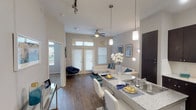 This single-floor residence offers a thoughtfully designed open-concept layout that seamlessly connects the kitchen, dining, and living areas. The living room is bright and welcoming, featuring wood-style flooring, elevated ceilings, a ceiling fan, and French doors that invite natural light and provide outdoor access. Pendant lighting above the kitchen island adds a modern touch to the space.

The kitchen is well-equipped with dark espresso cabinetry reaching toward the ceiling, granite-style countertops, black appliances including a refrigerator, range, and microwave, and a double-basin sink set into a peninsula island. Track lighting illuminates the workspace efficiently, and light wood-style flooring completes the clean aesthetic.

Both bedrooms are carpeted and comfortably sized, each featuring ceiling fans and windows that bring in natural light and outdoor views. The neutral gray walls provide a calm, versatile backdrop throughout.

The bathroom includes a full tub-and-shower combination with tile surround, tile flooring, and convenient access to a walk-in closet and in-unit laundry area. The overall design of the space balances modern finishes with functional, everyday living in a cohesive and neutral color palette.