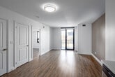 Located on the fourth floor at 460 Belmont Ave W in Kitchener, Ontario, this one-bedroom, one-bathroom unit features a thoughtfully designed open-concept layout finished with light-toned laminate flooring throughout. The kitchen is well-appointed with high-gloss white cabinetry extending to the ceiling, a neutral tile backsplash, stainless steel appliances including a refrigerator, electric range, and over-the-range microwave, a double stainless steel sink, and a dishwasher. A peninsula counter extends outward, providing additional workspace and a natural division between the kitchen and the adjacent living area. The living room benefits from floor-to-ceiling sliding glass doors that lead to a balcony, allowing generous natural light and outdoor views of the surrounding neighbourhood. The bedroom is a comfortable size, featuring a large window with views of the Kitchener skyline, laminate flooring, and direct access to a dedicated walk-in closet equipped with built-in shelving and a hanging rod. The bathroom offers a clean, contemporary finish with large-format tile flooring, a white vanity, and a full soaker tub with tiled surround. Throughout the unit, crisp white trim and neutral wall tones contribute to a bright, modern aesthetic.