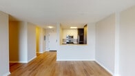 Located at 150 W St Charles Rd in Lombard, Illinois, this single-floor residential unit offers a clean, modern aesthetic throughout. The open-concept living area is highlighted by warm hardwood-style flooring that flows seamlessly from the entryway into the main living space, which features a sliding glass door leading to a private balcony with outdoor views of the surrounding neighborhood.

The kitchen is designed for functionality and style, featuring a peninsula layout with stainless steel appliances — including a range, over-the-range microwave, and refrigerator — complemented by white upper cabinetry, dark lower cabinetry, quartz countertops, and a classic subway tile backsplash. The peninsula provides convenient bar-style seating and opens directly to the living area, making it ideal for entertaining.

The bedrooms are carpeted for comfort and each includes a large window that allows ample natural light and views of the exterior surroundings. The unit includes two full bathrooms, each finished with tile flooring, a dark wood vanity, and a tub-shower combination enclosed by sliding glass doors. The overall color palette is neutral and bright, with white walls and warm accent tones creating a welcoming ambiance throughout the space.