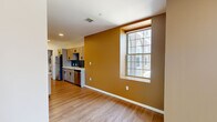 Located at 201 S Huntington Ave in Boston's Jamaica Plain neighborhood, this 2-bedroom, 2-bathroom unit offers a well-designed, single-floor layout. Warm hardwood-style flooring runs throughout, complemented by a color palette of earthy golden-amber and neutral tones that create an inviting ambiance.

The open-concept living, dining, and kitchen area is anchored by a galley-style kitchen featuring gray shaker cabinetry with matte black hardware, quartz countertops, a dark subway tile backsplash, and a full suite of stainless steel appliances. An in-unit stacked laundry is also conveniently included.

The living and dining area benefits from large grid-pane windows that bring in generous natural light and views of the surrounding Boston streetscape. Both bedrooms offer clean, bright interiors with the same hardwood-style flooring; the primary bedroom includes a double-door closet for ample storage.

The bathrooms are thoughtfully finished, with one featuring hexagonal floor tile, full subway tile surround, a soaking tub, and a window for natural ventilation. The unit's layout is efficient and functional, making excellent use of its compact footprint while maintaining a modern, cohesive aesthetic throughout.
