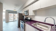 Located at 742 S Westlake Ave in Los Angeles, this one-bedroom, one-bathroom unit offers a compact yet efficient single-floor layout with a clean, modern aesthetic. The open living area is finished with smooth grey flooring and neutral grey walls, creating a bright and cohesive atmosphere. Sliding glass doors lead to a private balcony, allowing natural light to pour into the main living space, which is further complemented by an additional side window framing views of the surrounding Westlake neighborhood.

The kitchen runs along one wall in a galley-style configuration, featuring white flat-front cabinetry extending to the ceiling for ample storage. A bold purple countertop adds a distinctive design accent, paired with stainless steel appliances including a gas range, over-the-range microwave, and refrigerator.

The spacious bedroom offers generous room for furnishings and includes a mirrored sliding-door closet that enhances the sense of openness. The full bathroom is neatly appointed with a white tiled tub-shower combination, a large wall mirror, and a frosted glass transom window that provides natural light while maintaining privacy. The overall design is functional and contemporary, well-suited for urban living in central Los Angeles.