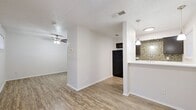 This 1-bedroom, 1-bathroom unit is thoughtfully laid out across a single floor, offering a functional and cohesive living environment. Wood-style plank flooring flows consistently throughout the space, creating a warm and unified aesthetic. The combined kitchen and living room serves as the heart of the unit, where a peninsula-style breakfast bar separates the two areas while maintaining an open feel. The kitchen is appointed with dark cabinetry, a black refrigerator, a mosaic tile backsplash, and pendant lighting that adds a stylish accent overhead. The living area benefits from a ceiling fan with light fixture, textured ceilings, and a clean, neutral color palette that maximizes the sense of space. The bedroom is a comfortable, private retreat featuring its own ceiling fan, a window for natural light, and a closet with bi-fold doors for convenient storage. The bathroom includes a full tub and shower combination with white tile surround, wood-style flooring, and a clean, functional design. A dedicated utility room and additional closet space round out the layout, providing practical storage solutions throughout the unit.
