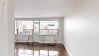 Located on the fourth floor at 2220 Weston Rd in Toronto's Weston neighbourhood, this one-bedroom, one-bathroom unit offers a well-organized layout across a comfortable single floor. The living room is a standout space, featuring large windows that flood the room with natural light and frame views of the surrounding residential streetscape. Polished parquet hardwood flooring runs throughout the living and bedroom areas, adding warmth and classic character to the clean, neutral palette. Baseboard radiators provide efficient heating throughout. The kitchen is thoughtfully designed with white cabinetry, dark countertops, a breakfast bar, gleaming tile floors, and a full suite of stainless steel appliances including a refrigerator, stove, and built-in microwave. The bedroom is a well-proportioned retreat with its own window overlooking neighbouring buildings, a built-in closet with panelled doors, and the same rich parquet flooring. The bathroom is finished with floor-to-ceiling white subway tile, a soaking tub with shower, a vanity with sink, and bright overhead lighting. A dedicated entrance completes the functional layout of this clean, move-in ready unit.