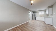 Located at 425 W Taft St in Wichita, Kansas, this efficient one-bedroom, one-bathroom unit offers a thoughtfully organized layout across a single floor. The open-concept kitchen and living area form the heart of the space, finished with warm luxury vinyl plank flooring and neutral gray walls that create a clean, modern aesthetic. The kitchen is well-appointed with crisp white shaker-style cabinetry, granite-look countertops, a stainless steel refrigerator, and a stainless range, providing all the essentials in a compact, functional footprint. A ceiling fan with a light kit serves the living area, while a wall-mounted HVAC unit ensures year-round comfort. Natural light filters in through windows fitted with white blinds. The bedroom offers a comfortable and private retreat, featuring the same durable LVP flooring, a ceiling fan, a window for natural light, and a reach-in closet with a full-width hanging rod for convenient storage. A hallway connects the main living spaces to the bathroom, which features a full tub and shower combination with white tile surround, chrome fixtures, and white cabinetry. The consistent use of neutral tones and modern finishes throughout gives this unit a cohesive and well-maintained character.