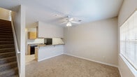 This two-story home in Lafayette, Louisiana offers five bedrooms and three full bathrooms spread across two well-proportioned floors. The main level features an open-concept living and dining area with plush wall-to-wall carpet, a ceiling fan with light fixture, and a tiled entryway with a front-facing window that brings in natural light. The kitchen flows seamlessly from the living space via a breakfast bar with granite-style countertops, and is equipped with honey-toned wood cabinetry, tile flooring, a double sink, black appliances including a refrigerator and electric range, and ample upper and lower cabinet storage. A staircase connects the two floors, each offering generous room proportions. The five bedrooms are carpeted and finished with neutral tones, providing versatile living spaces. The spacious primary bedroom offers notable square footage among the bedrooms. The three bathrooms are consistent in finish, each featuring tile flooring, a tub-shower combination with curved curtain rod, granite-style vanity countertops, and wood cabinetry. Neutral wall tones and white trim run throughout the home, contributing to a clean, cohesive aesthetic well-suited for comfortable everyday living.
