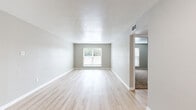 This single-floor residence offers a clean, contemporary design defined by a neutral color palette and thoughtfully selected finishes. The open living and dining areas are finished with light-toned wood-style flooring that enhances the sense of space and brightness, complemented by textured ceilings and white baseboards throughout. Generous windows dressed with horizontal blinds allow natural light to flow freely into the main living spaces, creating an airy, welcoming atmosphere.

The kitchen features stainless steel appliances, including an electric range and over-the-range microwave, paired with white quartz-style countertops and a classic white subway tile backsplash. Light wood cabinetry and a window with blinds add both function and brightness to the space.

The bedrooms are carpeted for comfort and each includes a wide sliding-door closet with built-in shelving and hanging rods, offering ample storage. The bathroom presents a sleek, modern vanity with a white countertop, under-mount sink, framed mirror, and contemporary light fixtures. Light wood-style flooring continues into the bathroom, maintaining a cohesive look throughout.

A connecting hallway links the bedroom and bathroom areas seamlessly, reinforcing the practical and well-organized layout of this inviting single-floor home.