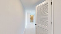 Located at 150 S Bryan Rd in Dania Beach, Florida, this three-bedroom, two-bathroom residence offers a well-designed single-floor layout with a clean, contemporary aesthetic throughout. Light wood-style flooring flows seamlessly across all rooms, complemented by crisp white walls and modern finishes that create a bright, airy atmosphere.

The kitchen is a standout feature, showcasing high-gloss white upper cabinetry, wood-toned lower cabinets, a subway tile backsplash, light quartz countertops, and a full suite of stainless steel appliances including a range, microwave, dishwasher, and French door refrigerator. Track lighting overhead adds a modern touch. The kitchen opens directly to a hallway and living area, promoting an open, connected feel.

Each of the three bedrooms is well-proportioned and filled with natural light through large windows framing expansive views of the Dania Beach skyline and lush treetops. The bedrooms feature double-door closets with sleek black hardware, adding a refined contrast to the otherwise all-white palette.

The two bathrooms are finished with neutral tile, modern vanities with wood-toned cabinetry, and a tub-shower combination with tile surround. Clean lines and recessed lighting maintain the contemporary feel throughout. Two hallways connect the rooms efficiently, and a dedicated closet provides additional storage.