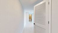 Located at 150 S Bryan Rd in Dania Beach, Florida, this three-bedroom, two-bathroom residence offers a well-designed single-floor layout with a clean, contemporary aesthetic throughout. Light wood-style flooring flows seamlessly across all rooms, complemented by crisp white walls and modern finishes that create a bright, airy atmosphere.

The kitchen is a standout feature, showcasing high-gloss white upper cabinetry, wood-toned lower cabinets, a subway tile backsplash, light quartz countertops, and a full suite of stainless steel appliances including a range, microwave, dishwasher, and French door refrigerator. Track lighting overhead adds a modern touch. The kitchen opens directly to a hallway and living area, promoting an open, connected feel.

Each of the three bedrooms is well-proportioned and filled with natural light through large windows framing expansive views of the Dania Beach skyline and lush treetops. The bedrooms feature double-door closets with sleek black hardware, adding a refined contrast to the otherwise all-white palette.

The two bathrooms are finished with neutral tile, modern vanities with wood-toned cabinetry, and a tub-shower combination with tile surround. Clean lines and recessed lighting maintain the contemporary feel throughout. Two hallways connect the rooms efficiently, and a dedicated closet provides additional storage.