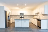 Located at 45 Yarmouth Street in Guelph, Ontario, this well-appointed 3-bedroom, 4-bathroom unit offers a generous and thoughtfully designed layout across a single floor. The open-concept living and kitchen area forms the heart of the unit, featuring wide-plank wood-look flooring, crisp white walls, and abundant natural light streaming in through large windows and a glass-panel door leading to a private balcony with pleasant neighbourhood views. The kitchen is outfitted with sleek white cabinetry extending to the ceiling for ample storage, grey countertops, a tiled backsplash, and stainless steel appliances including a French door refrigerator. The generous primary bedroom provides a comfortable retreat, while the two additional bedrooms offer versatile spaces with the same consistent flooring and neutral finishes throughout. The four bathrooms feature light wood-toned vanities, modern fixtures, and clean tile flooring. A dedicated in-unit laundry room houses a full-size front-loading washer and dryer. Bright, well-lit hallways connect each room seamlessly. The overall aesthetic is modern and neutral, creating a clean, move-in-ready environment suited for a variety of living arrangements.