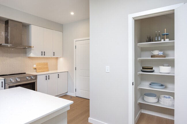 Cocina de casa adosada con gabinetes blancos, encimeras de cuarzo blanco y protector contra salpicaduras de azulejos beige. - Avalon Brier Creek