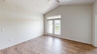 Located in Youngsville, Louisiana, this well-appointed 2-bedroom, 2-bathroom single-story home offers a thoughtfully designed open-concept layout. The kitchen serves as the heart of the home, showcasing rich dark-stained cabinetry, granite countertops, a subway tile backsplash, stainless steel appliances including a range, microwave, and refrigerator, and a large center island with a built-in sink and pendant lighting overhead. The kitchen flows seamlessly into the living area, which features wood-look flooring, vaulted ceilings, a ceiling fan, and glass French doors with transom windows that invite natural light and provide access to an outdoor balcony area. The primary bedroom impresses with soaring vaulted ceilings, dual windows, a ceiling fan, and plush carpeting, complemented by a dedicated walk-in closet with wire shelving. The second bedroom is equally comfortable with carpeted floors, a ceiling fan, and a bright window. Two full bathrooms include a tub-shower combination with built-in shelving and wood-look flooring. A dedicated laundry room accommodates a full-size washer and dryer side by side. This home combines modern finishes with functional living spaces throughout.