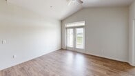 Located in Youngsville, Louisiana, this well-appointed 2-bedroom, 2-bathroom single-story home offers a thoughtfully designed open-concept layout. The kitchen serves as the heart of the home, showcasing rich dark-stained cabinetry, granite countertops, a subway tile backsplash, stainless steel appliances including a range, microwave, and refrigerator, and a large center island with a built-in sink and pendant lighting overhead. The kitchen flows seamlessly into the living area, which features wood-look flooring, vaulted ceilings, a ceiling fan, and glass French doors with transom windows that invite natural light and provide access to an outdoor balcony area. The primary bedroom impresses with soaring vaulted ceilings, dual windows, a ceiling fan, and plush carpeting, complemented by a dedicated walk-in closet with wire shelving. The second bedroom is equally comfortable with carpeted floors, a ceiling fan, and a bright window. Two full bathrooms include a tub-shower combination with built-in shelving and wood-look flooring. A dedicated laundry room accommodates a full-size washer and dryer side by side. This home combines modern finishes with functional living spaces throughout.