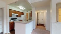 This single-story residence is thoughtfully laid out to maximize functionality and comfort throughout. The kitchen is equipped with warm wood cabinetry, a gas range, white refrigerator, and a peninsula with a built-in sink that opens toward the entryway corridor, creating an efficient and connected flow. An adjacent utility area accommodates an in-unit washer and dryer, adding everyday convenience. Dark hardwood-style flooring runs through the kitchen and utility spaces, offering a practical contrast to the light-toned countertops.

The living room stands out with a vaulted ceiling and ceiling fan, creating an airy, open atmosphere. A large window allows natural light to fill the space, enhancing its spacious feel. Multiple bedrooms feature plush carpeting, ceiling fans, and generous windows fitted with vertical blinds. At least one bedroom includes a walk-in closet with shelving. The unit includes two full bathrooms, each featuring a tiled shower-tub combo. One bathroom showcases rich wood-tone cabinetry and hardwood-style flooring, while the other offers a clean, minimal design with textured walls.