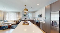Located at 200 Henry Hill St in Cary, NC, this single-floor residence offers a thoughtfully designed layout with stylish finishes throughout. The kitchen serves as a centerpiece, showcasing a striking two-tone cabinet scheme with white upper cabinets and gray lower cabinets accented by gold hardware. A generous island with a quartz countertop anchors the space, complemented by stainless steel appliances, subway tile backsplash, and bold brass pendant lighting. The kitchen flows seamlessly into the living area, where large windows invite ample natural light and linen drapes frame the views.

The dining area features direct access to a private balcony through a glass door, creating an airy indoor-outdoor connection. Light wood flooring runs throughout, lending warmth and continuity to the home.

The bedrooms are serene retreats, highlighted by sage green accent walls and large windows with plantation shutters. One bedroom features a ceiling fan and direct access to an en-suite bathroom. The primary bathroom offers a dual-sink vanity with white cabinetry, a glass-enclosed shower, and light wood flooring. A well-organized walk-in closet with multi-tier shelving and hanging rods provides generous storage. Every detail of this home reflects a clean, modern aesthetic.