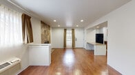 Located at 711 S Main St in Wichita, Kansas, this single-floor unit offers a well-designed, open-concept layout that maximizes living space and functionality. Rich hardwood flooring flows throughout the main living areas, reflecting natural light from the front-facing window dressed in warm gold curtains, giving the space a welcoming ambiance.

The spacious living area is anchored by a striking floor-to-ceiling stone tile fireplace surround, serving as a prominent focal point. Recessed lighting throughout the ceiling provides even, consistent illumination. A built-in wall unit air conditioner ensures year-round comfort.

The layout transitions seamlessly into a dedicated kitchen area, equipped with warm wood cabinetry, a tile backsplash, and a full suite of black appliances including a refrigerator, electric range, over-the-range microwave, and dishwasher. A built-in countertop peninsula provides additional prep and dining space, while open shelving adds a practical design touch.

A white paneled front entry door with exterior access adds to the unit's convenience and security. The bathroom includes a full-size soaking tub with a surround enclosure. Throughout the space, clean white walls and consistent flooring materials create a cohesive, neutral palette that is both modern and functional.