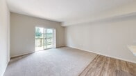 Located on Berkshire Hills Drive in Sunbury, Ohio, this single-floor, one-bedroom, one-bathroom unit offers a well-organized and efficiently designed layout. The combined kitchen and living room serves as the heart of the space, featuring light hardwood-style flooring, neutral walls, and a seamless open-concept flow. The kitchen is equipped with stainless steel appliances — including a refrigerator, range, and microwave — complemented by dark espresso cabinetry, light granite-style countertops, and a peninsula with a built-in sink that doubles as a breakfast bar. A sliding glass door in the living area opens to a private balcony with wood-plank flooring and metal railing, offering open views of the surrounding community and greenery. The bedroom is a comfortable, carpeted retreat featuring a closet, large windows with blinds that invite natural light, and clean neutral tones. A hallway connects the rooms and provides additional storage access. The bathroom includes a full tub and shower combination with clean white surround and tile flooring. Throughout the unit, consistent use of warm neutral tones, white trim, and panel-style doors creates a cohesive and move-in-ready aesthetic.