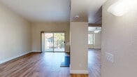 Located at 9375 N Saybrook Dr in Fresno, CA, this one-bedroom, one-bathroom home offers a thoughtfully designed single-floor layout with a warm and inviting ambiance throughout. The living room is an immediate standout, boasting soaring vaulted ceilings that lend an airy, open feel to the space. A marble-surround fireplace serves as an elegant focal point, while sliding glass doors flood the room with natural light and provide direct access to a private balcony with views of the surrounding neighborhood and mature trees. Consistent hardwood-style flooring runs throughout, tying each room together seamlessly. The galley-style kitchen is well-appointed with crisp white cabinetry, dark granite countertops, stainless steel appliances including a refrigerator, electric range, microwave, and dishwasher, and a double basin sink beneath a window. The bedroom offers a comfortable and private retreat with a ceiling fan, a natural light-filled window, and easy access to a dedicated closet. The full bathroom features tile flooring, a granite-topped vanity with a large mirror, and a tub-shower combination with sliding glass enclosure. Clean neutral tones and plentiful natural light give the entire home a bright, welcoming character.