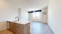 This well-appointed 2-bedroom, 2-bathroom residence at 55 Washington Street in East Orange, NJ offers a thoughtfully designed single-floor layout with modern finishes throughout. Light wood-tone luxury vinyl flooring flows seamlessly across the entire unit, complementing the clean white walls and creating a bright, cohesive aesthetic.

The open-concept kitchen and living area serves as the heart of the home. The kitchen features wood-grain cabinetry with sleek hardware, white quartz countertops, stainless steel appliances including a gas range and built-in microwave, a dishwasher, and a peninsula with an undermount sink — ideal for both cooking and casual entertaining. A contemporary linear pendant light anchors the space above.

The spacious primary bedroom is flooded with natural light through large corner windows that frame sweeping city skyline views, making it a true standout. Both bedrooms include built-in closets with shelving and hanging storage. The hallway connects all rooms efficiently, maintaining a functional flow throughout.

The two bathrooms are finished in neutral tile. The primary bathroom features large-format floor tile and a glass-enclosed walk-in shower with marble-style wall tile and matte black fixtures. The second bathroom offers a clean, minimalist design. Recessed lighting throughout enhances the modern ambiance of this move-in-ready residence.