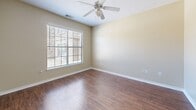 Located at 3131 Simpson Stuart Rd in Dallas, TX, this two-story home offers a well-organized layout across two floors. The ground floor features an entrance, an attached garage with an automatic opener and concrete flooring, and an open-concept kitchen and living area. The kitchen is equipped with light wood cabinetry, a peninsula island with a sink, white appliances including a dishwasher and range, and a window that brings in natural light. The adjoining living room continues the warm hardwood-style flooring, features a ceiling fan, and is anchored by a large window with exterior views. A staircase connects the two levels. The upper floor hosts both bedrooms and bathrooms. The spacious primary bedroom includes plush carpeting, a ceiling fan, and direct access to its own bathroom. The second bedroom also features carpeting, a ceiling fan, and a natural light-filled window. Both bathrooms are fitted with hardwood-style flooring, a tub-shower combination, vanity cabinetry, and clean white fixtures. A dedicated closet provides additional storage. The home's neutral warm-beige walls and consistent finishes throughout create a cohesive, functional living environment.