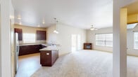 Located at 1701 Moon Meadows Dr in Rapid City, South Dakota, this well-appointed 2-bedroom, 2-bathroom single-floor home offers a thoughtfully designed layout with comfortable living spaces throughout. The open-concept kitchen and living area serves as the heart of the home, featuring rich dark-wood cabinetry, granite countertops, a central island with pendant lighting, and a seamless flow into a spacious carpeted living room equipped with a ceiling fan and ample natural light from large windows. A sliding door leads to a covered balcony supported by a stacked-stone column, offering open views of the surrounding South Dakota landscape. Both bedrooms are carpeted and feature walk-in closets with wire shelving for generous storage. The bathrooms are finished with dark-wood vanities, granite countertops, and tiled tub-shower surrounds accented with decorative mosaic tile. A dedicated in-unit laundry room houses a full-size washer and dryer. Additional highlights include an electrical panel neatly tucked into the hallway, multiple closets, and a neutral color palette throughout that lends a clean, move-in-ready ambiance to the entire home.