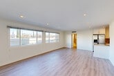 Located at 336 S Elm Dr in the heart of Beverly Hills, CA, this well-appointed one-bedroom, one-bathroom residence offers a thoughtfully designed layout across a single floor. The expansive living room is a standout feature, bathed in natural light through a wide bank of windows that frame outdoor views of the surrounding neighborhood. Light-toned hardwood-style flooring runs throughout the main living areas, complementing the clean white walls and recessed lighting overhead. Crown molding adds a refined architectural detail to the living space. The kitchen is efficiently designed with white shaker-style cabinetry, granite countertops, a diagonal-pattern stone tile backsplash, and stainless steel appliances, including a refrigerator and microwave. A peninsula counter creates a natural transition between the kitchen and living area. The spacious bedroom features plush carpeting, a window for natural light, and recessed lighting. The bathroom is finished with warm beige tile work surrounding a full bathtub and shower combination, complemented by a granite-topped vanity with modern hardware. A connecting hallway links the rooms seamlessly, creating a cohesive and functional flow throughout this well-maintained Beverly Hills residence.