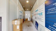 Located at 7303 S Peek Rd in Richmond, TX, this dedicated package management hallway serves as a centralized parcel hub for the surrounding residential community. The space is a single-floor corridor lined on both sides with Smart Package smart lockers, offering residents a secure and organized system for receiving deliveries at any time of day.

The hallway features a clean, utilitarian design with a concrete floor, a flat ceiling with recessed lighting, and security cameras mounted overhead to ensure safety and accountability. The locker units are branded with SmartHub and SmartCommunity by Ventera signage, promoting a connected living experience and encouraging residents to download the SmartHub mobile app for seamless parcel management.

At the far end of the corridor, a set of white double doors provides a closed boundary to the space, while the open entrance offers direct views of the broader residential complex, including covered parking and landscaped grounds. The layout is straightforward and efficiently organized, allowing residents to navigate the space with ease. Natural light filters in from the open entrance, complementing the overhead lighting and keeping the corridor bright and welcoming. Overall, the space is purpose-built for modern, tech-enabled package delivery convenience.